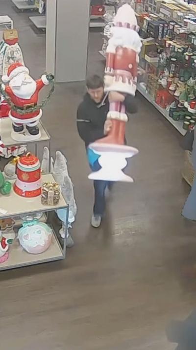 CCTV footage from inside TK Maxx shows a man with short light brown hair carrying a life-size nutcracker Christmas decoration