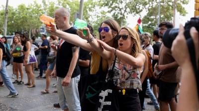 Two women point water pistols