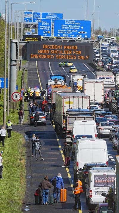 Road blocked with traffic with people walking on the hard shoulder 