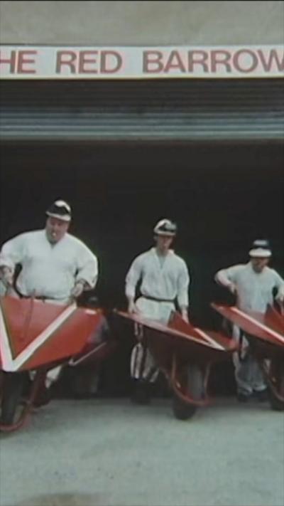 Three men in white boiler suits pushing red wheelbarrows