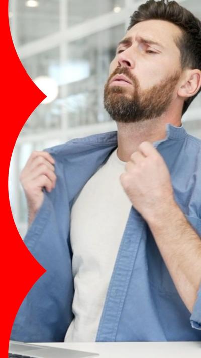 A man with short brown hair and a short brown beard holds his shirt away from his body