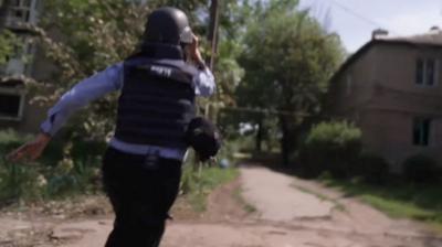 Yogita Limaye running from a drone attack. She is wearing a helmet and press vest.