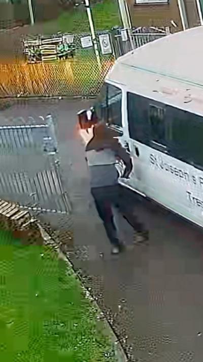 A man with a hood stands next to a minibus 