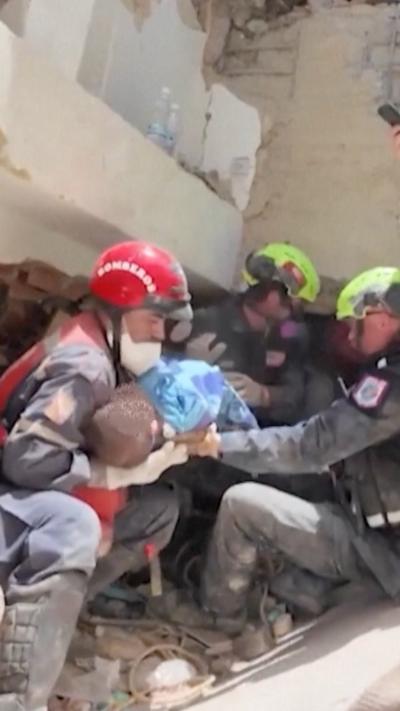 A baby being carried by rescue workers