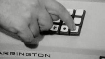 A hand pushes buttons on a computer for banking.