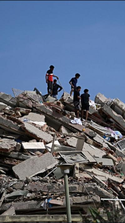 People stand on the rubble of a destroyed building in Verify branding