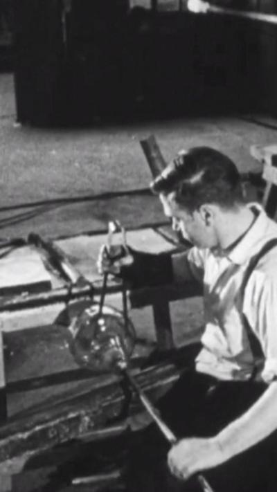 A black and white image of a glassblower at work