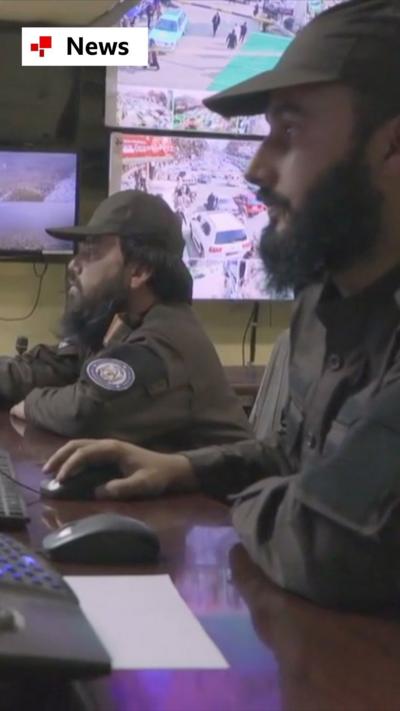 Two people sit in a CCTV control room