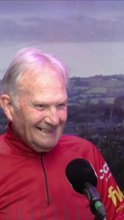 A smiling elderly man with white hair and wearing a red lycra top