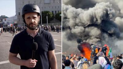 BBC's Carl Nasman is talking to a camera reporting on the immigration protests.