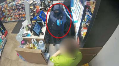 Robber aiming gun at worker