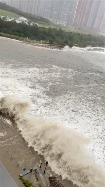 An aerial shot of large waves crash into a city shoreline in Hong Kong.
