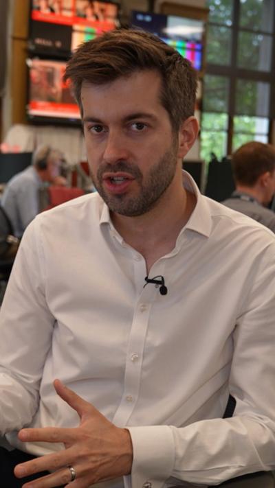 Reporter wearing long-sleeved white shirt looking at camera