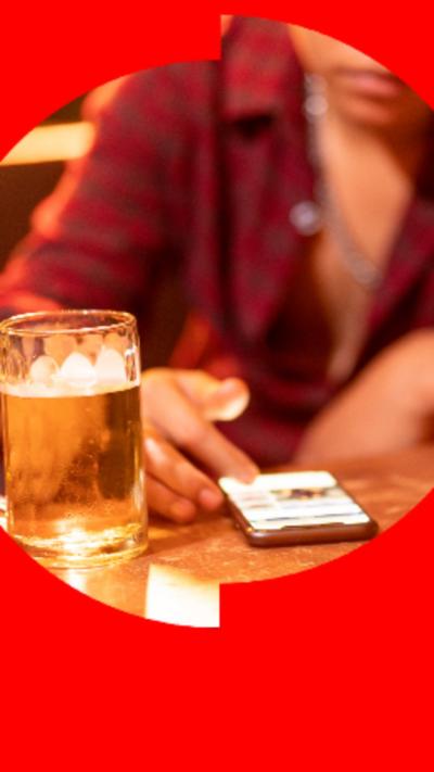 Woman watching her phone with a pint of beer next to it