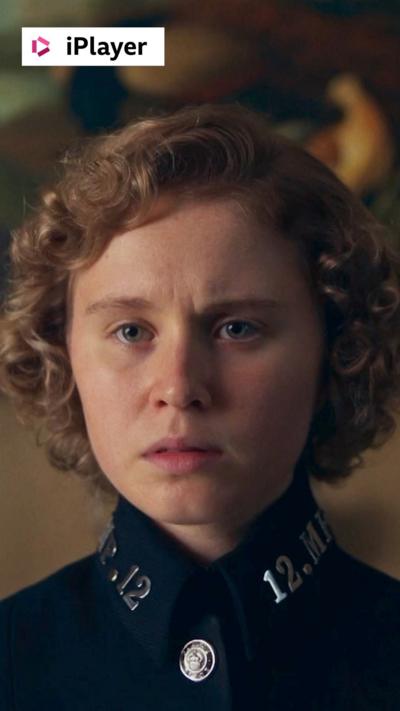 The character Violet looks concerned, dressed in a police uniform and sitting in front of a framed painting