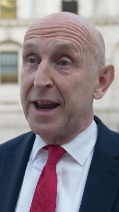 John Healey wears a red tie and blue suit