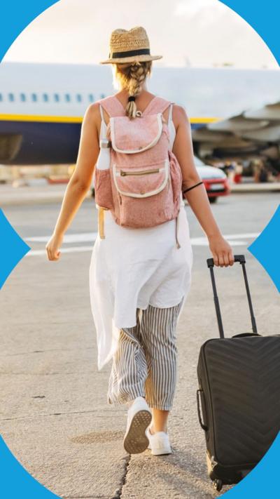 A woman with a suitcase walks towards a passenger aeroplane.