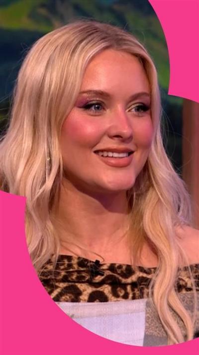 Zara Larsson sits in The One Show studio - she has long blonde hair and wears a top with leopard print edge