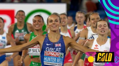 Georgia Hunter-Bell celebrates with her arms stretched out as she crosses the line for gold