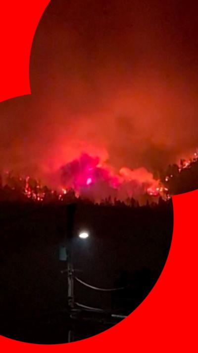 Plume of smoke and huge flames above forest at night