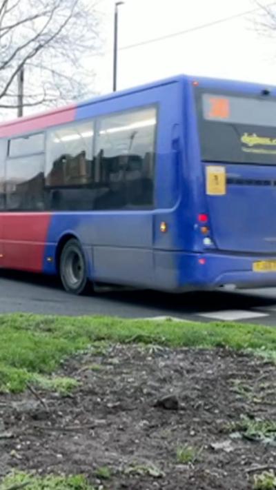 A blue and red bus travelling along a road