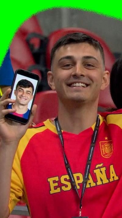 Spanish fan holds up a photo of Pedri on his phone to show the resemblance between the two of them.