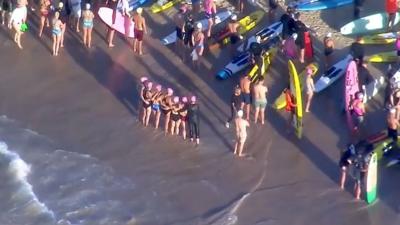 An aerial grab from video shows swimmers standing on the beach next to surfers with their boards before they paddle out, in Bondi on Friday.