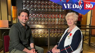 Ricky sits with Ruth Bourne in front of a Bombe machine replica