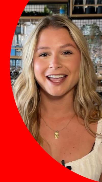 Mollie Pearce smiles in a bar. She has long wavy blonde hair and wears a white top