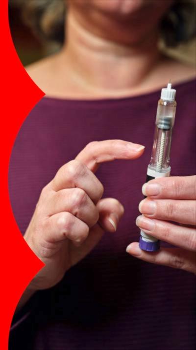 A woman holding a needle in one hand and pointing at it with the other hand. She wears a purple top. Face not visible.