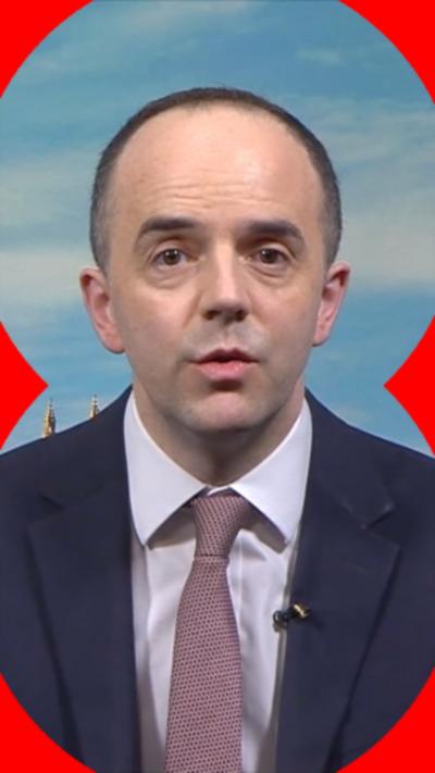 Health Secretary James Murray wearing a blue suit, lilac shirt and light brown tie.