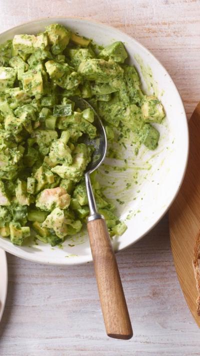 Green chicken sandwich filler in a white bowl with a spoon in it. 