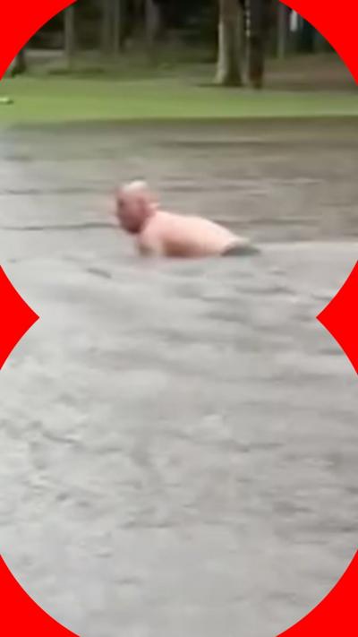 Man swimming on flooded golf course in Sydney
