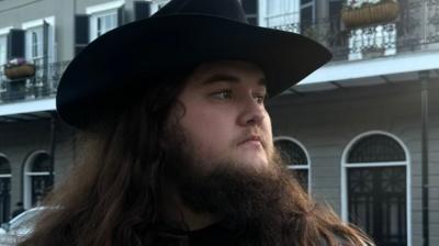 TikToker Kalani Smith, with cowboy hat and big brown beard, standing in the street