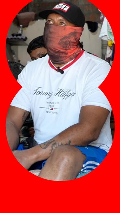 A man wearing a bandana over his face looks at someone off camera