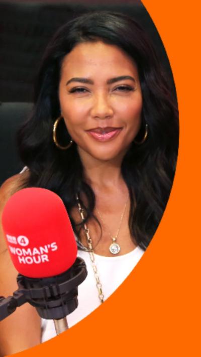 Emma Grede has long dark hair and is wearing a white top. She's sat in front of a red microphone.