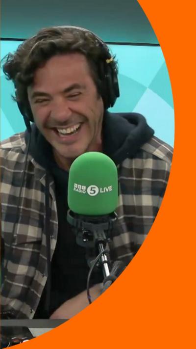 Jack Savoretti has dark hair and is wearing a grey-checked jacket with a black hood.