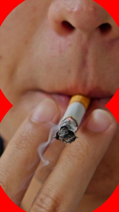 A close-up of a person's face showing a smoking cigarette in their mouth, and two fingers either side of it.