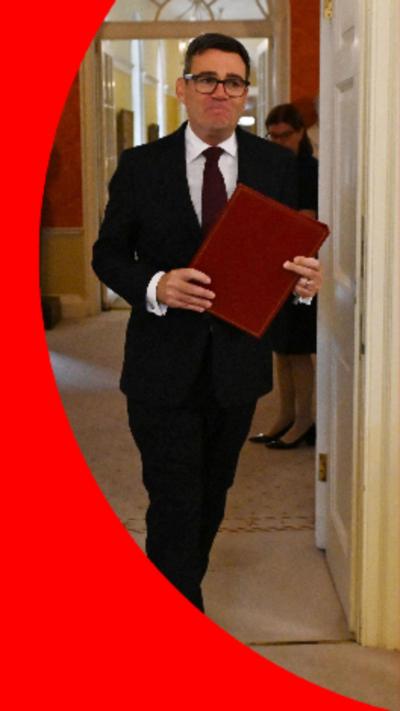 PM Andy Burnham holding a red folder