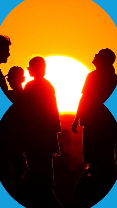 The silhouette of four people standing in front of the Sun