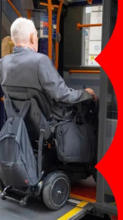 Elderly man in a wheelchair uses ramp to get onto a bus