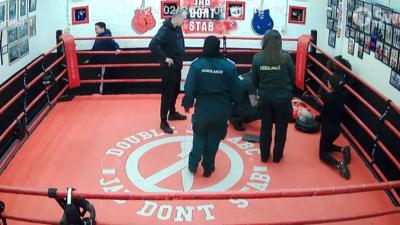 Jon Mckenna, lies on the canvas of a boxing ring. He is surrounded by colleagues and members of the ambulance service.