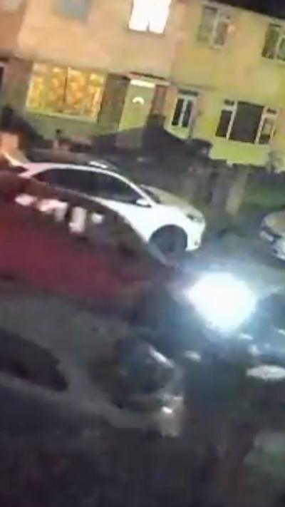 A car smashing into a stationary vehicle in front of a house