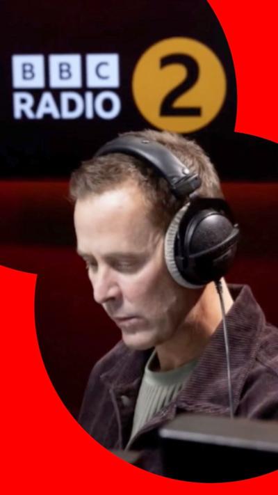 Scott Mills with headphones on in BBC Radio 2 studio 