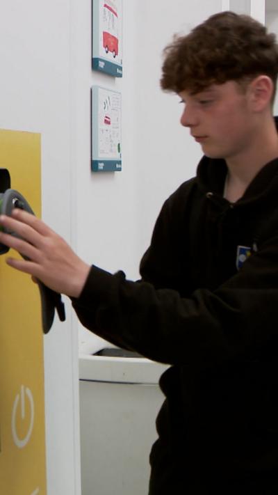School pupil wearing black locking away mobile phone