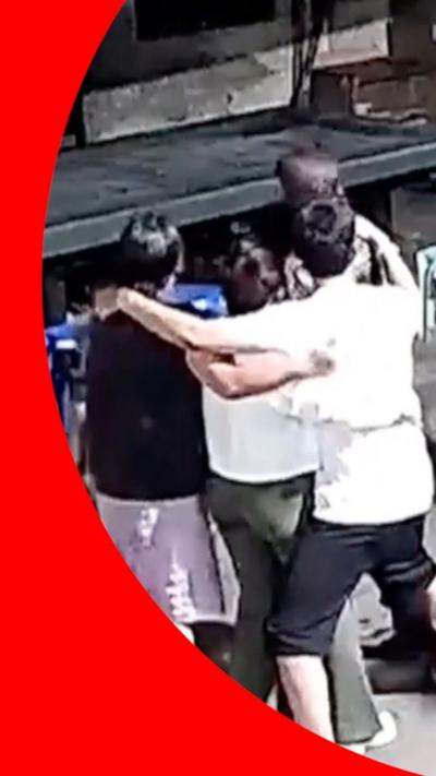 A photo of the backs of a group of four people holding onto each other