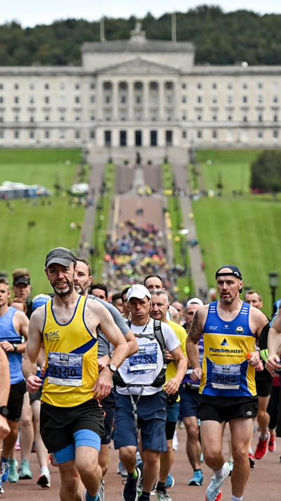 Runners take part in the Belfast Marathon. In the distance is Stormont buildings, but it is blurred.
