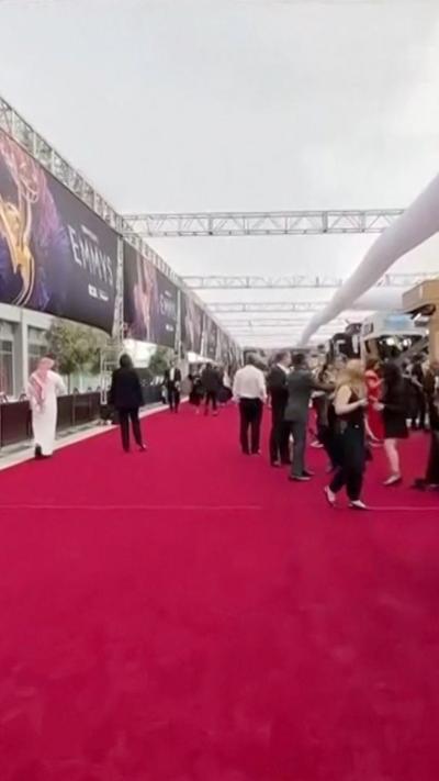 People standing wearing formal clothes on large red carpet at Emmys in downtown Los Angeles