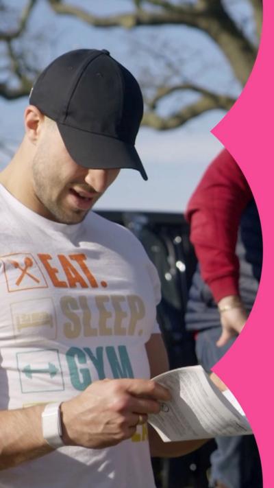A man, Tommy Fury, wearing a white tshirt and black cap looking at instructions