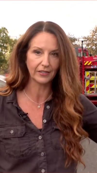 A woman with long hair stands in front of the camera 